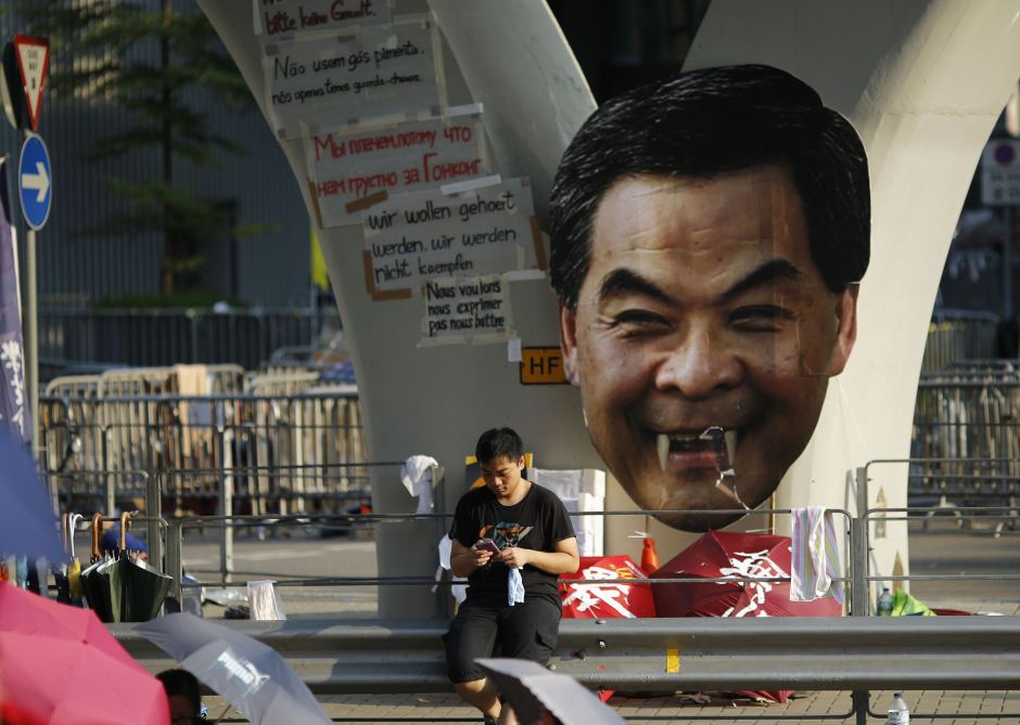 A protester sits next to a defaced cut-out of Hong Kong Chief Executive CY Leung while blocking a street outside the government headquarters in Hong Kong on Sept. 29 --- Reuters